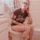 A blonde girl with tattoos and wearing glasses records herself shitting and pissing  while sitting on a toilet. Audible plop sounds. Video has vintage sepia color tones. Product and dirty TP shown. 720P HD. Over 2 minutes.